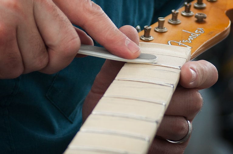 Fret polishing on a taped-off fingerboard
