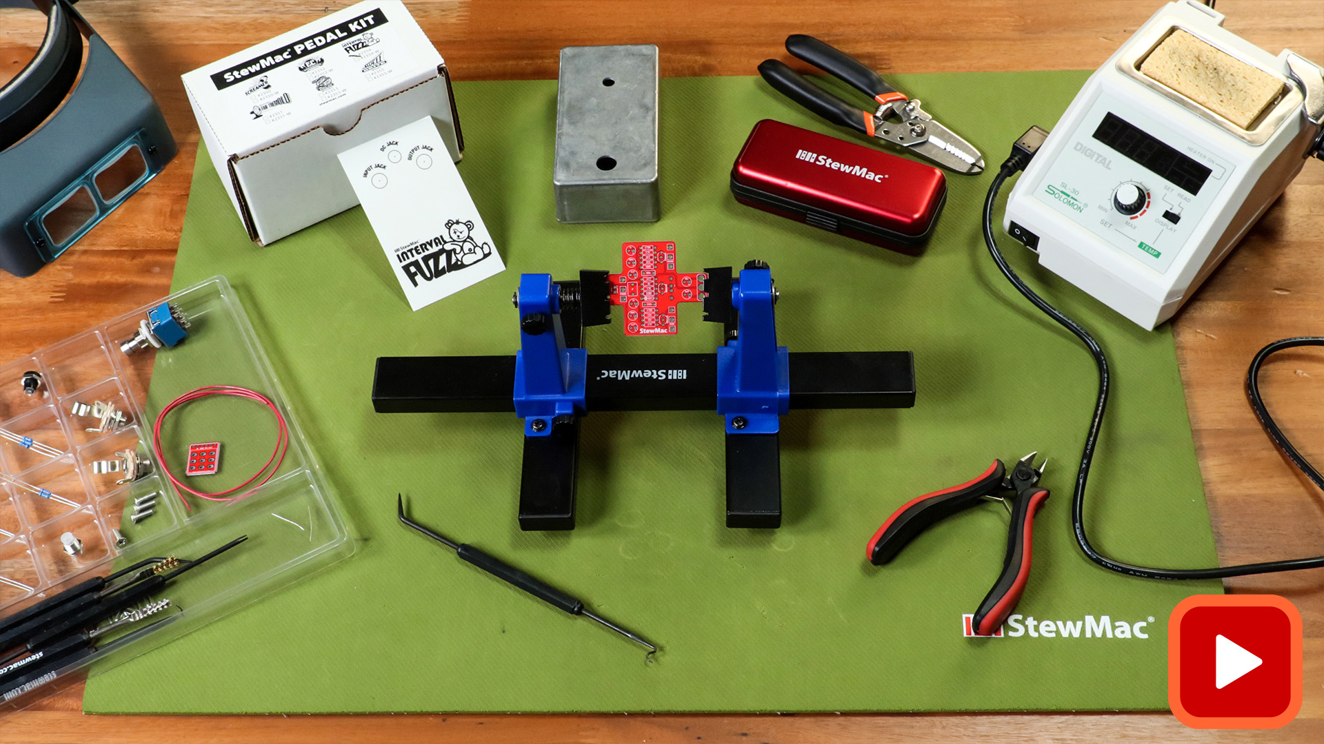 Pedal kit parts, soldering equipment, and tools on a bench 