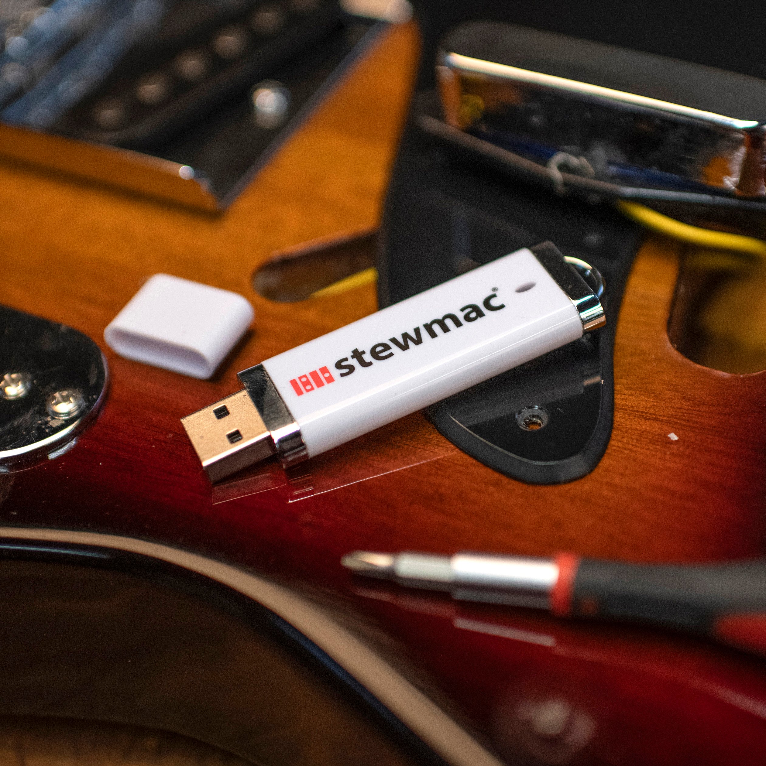 Portable thumbdrive preloaded with StewMac videos on a guitar with luthier tools.
