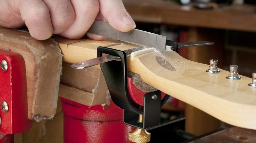 Filing a string nut slot on a guitar.