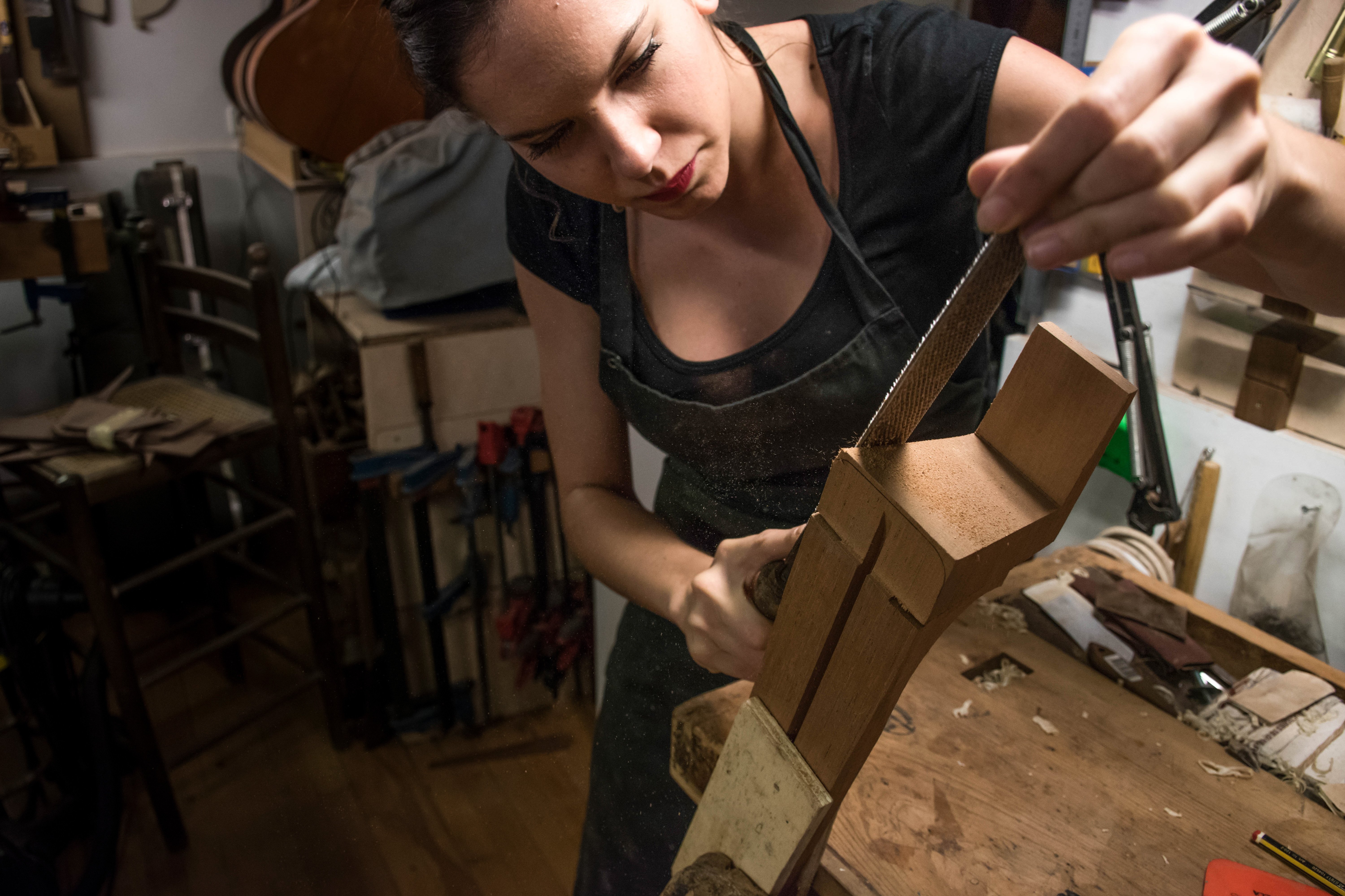 Woman carving acoustic guitar neck heel