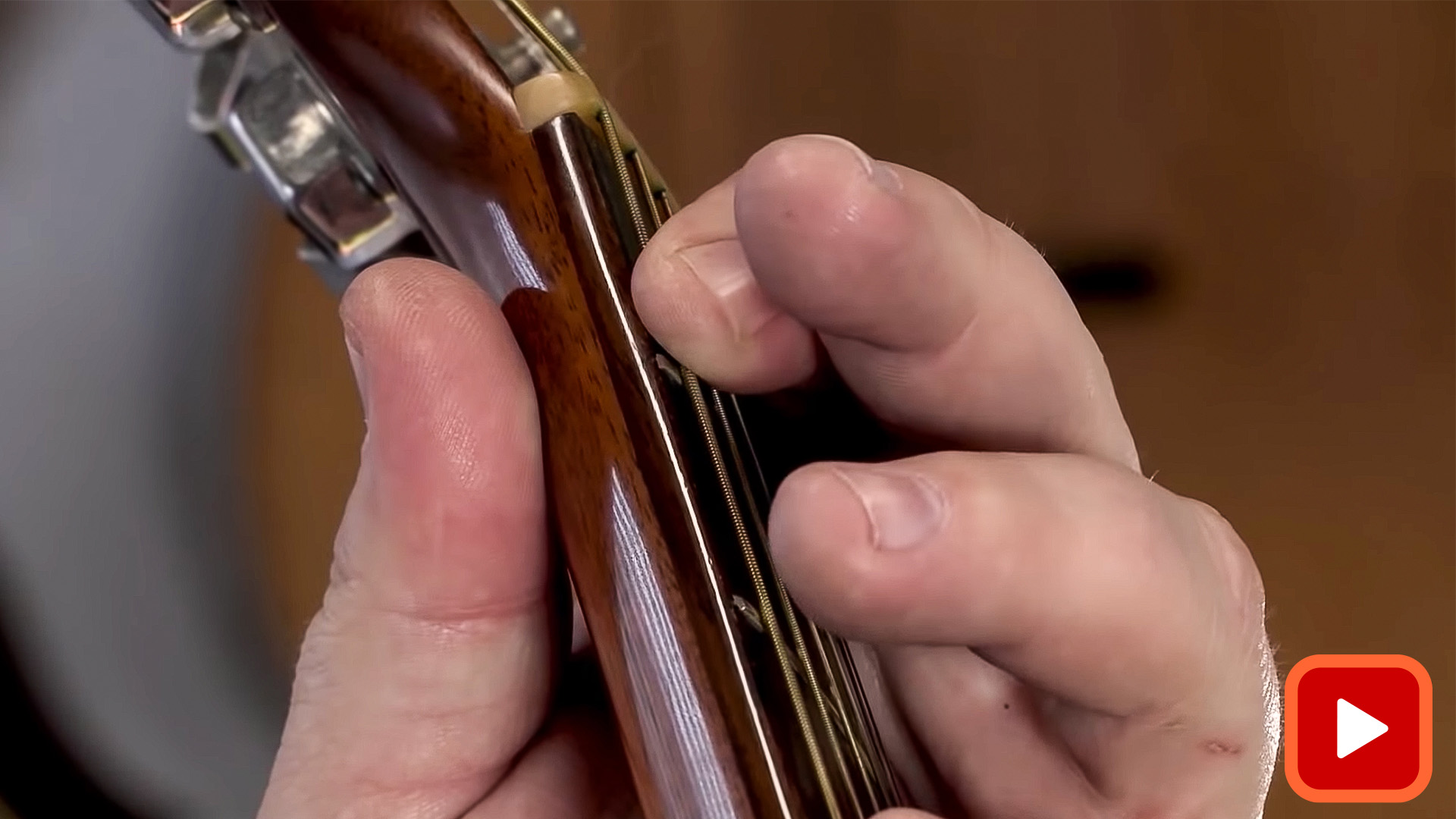 Fingers fretting strings on acoustic guitar neck