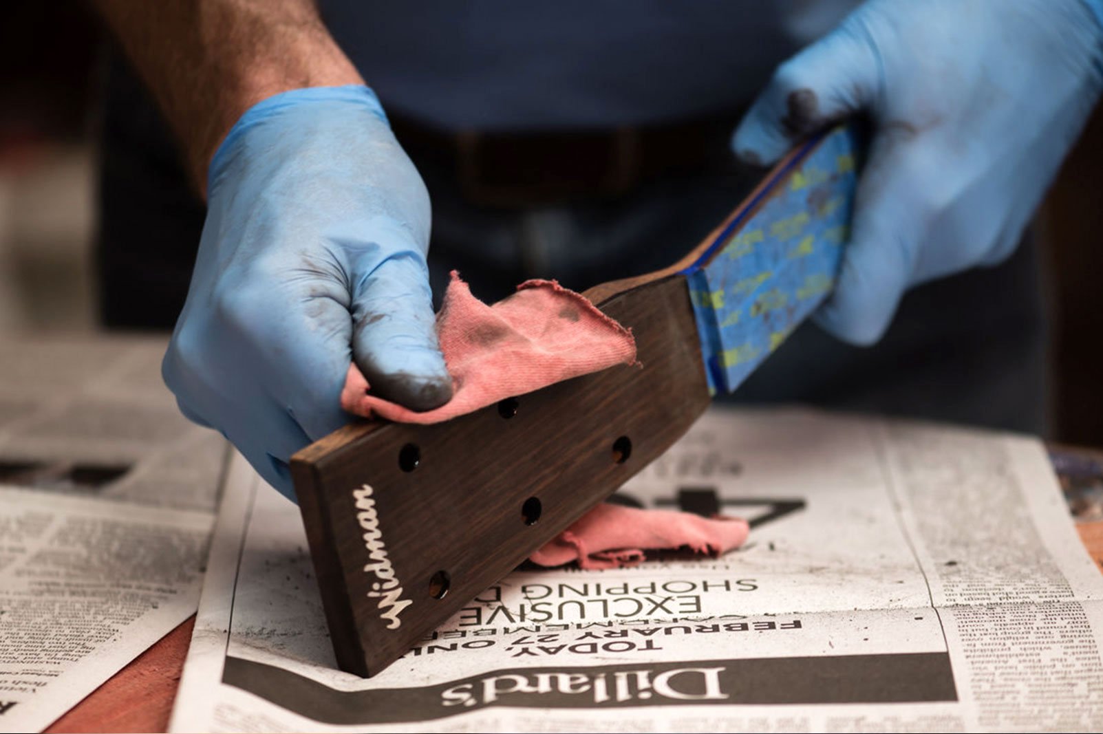 Acoustic guitar headstock with stain being wiped on