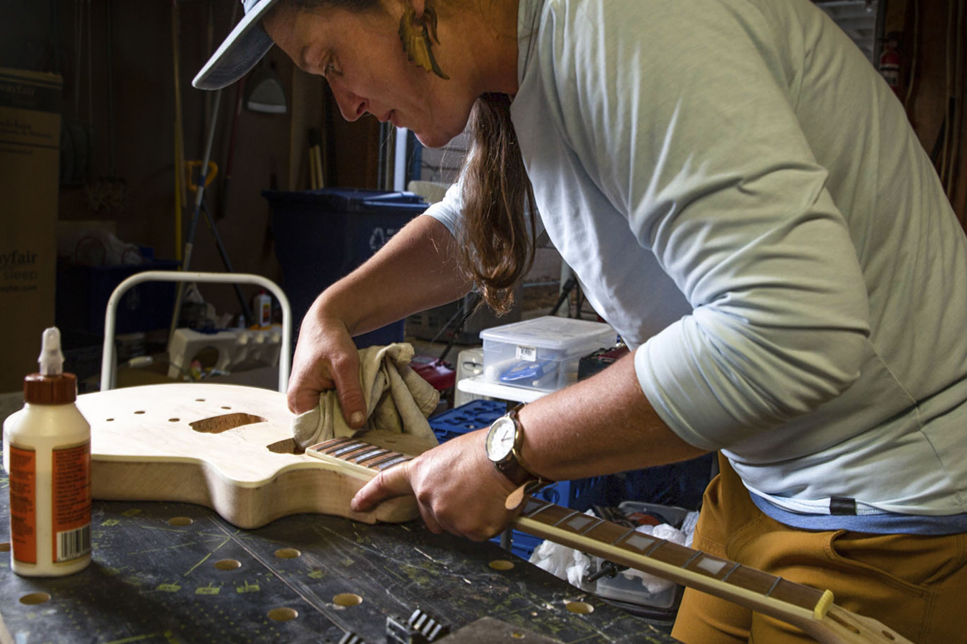 Woman gluing in neck on electric guitar