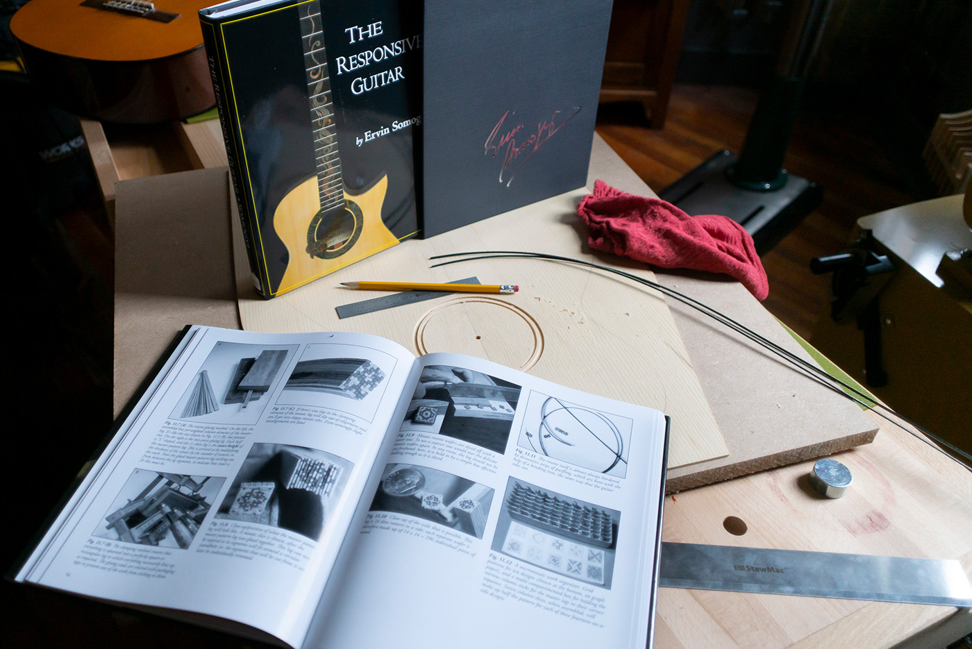 Book open on bench with wood, tools, and binding