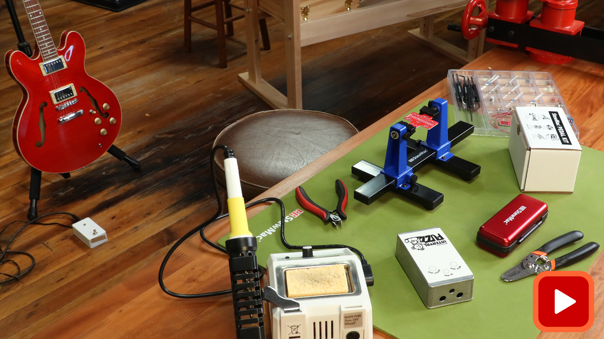 Pedal kit and tools on bench with guitar in background