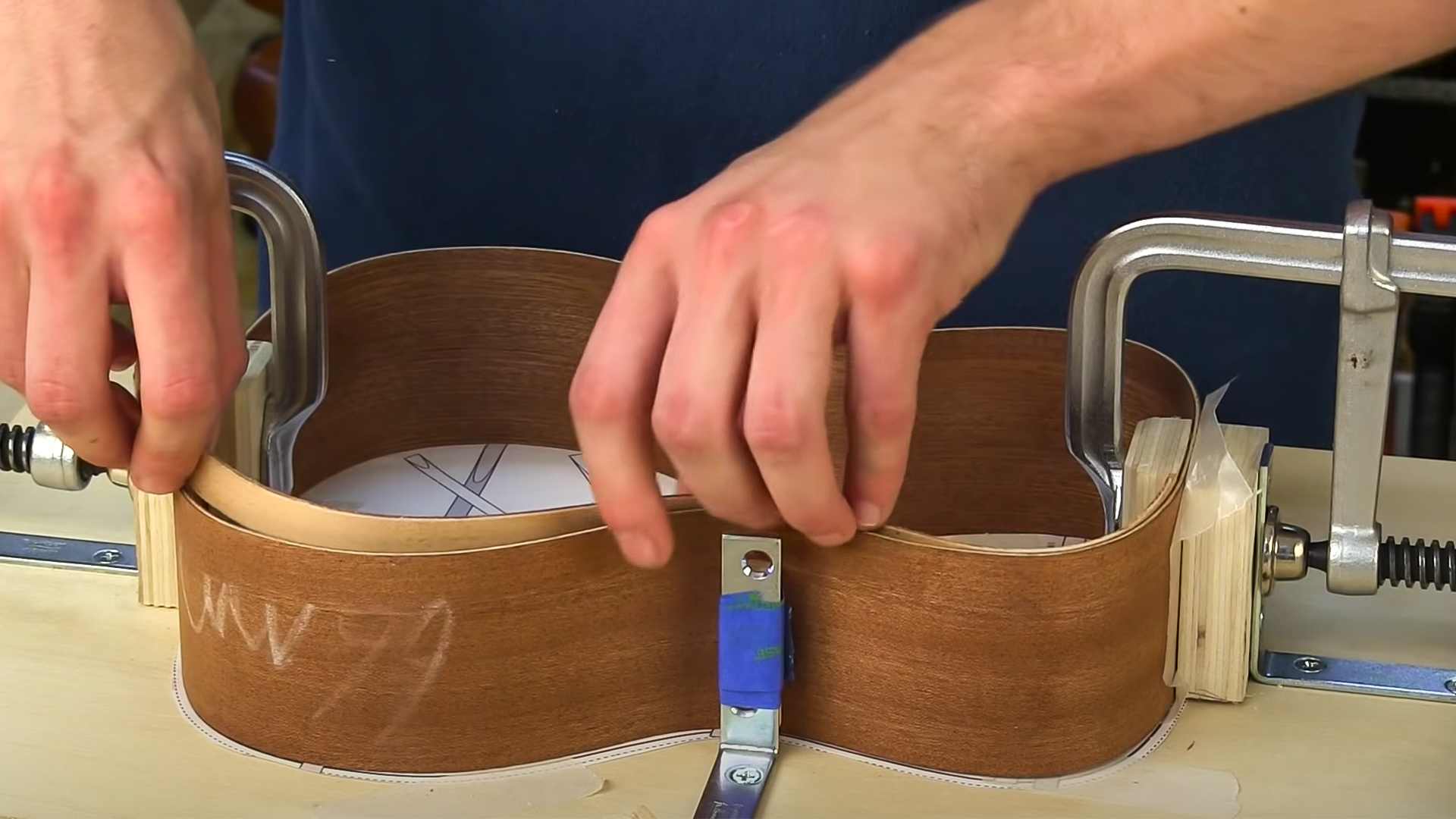 Hands fitting ukulele sides into body mold