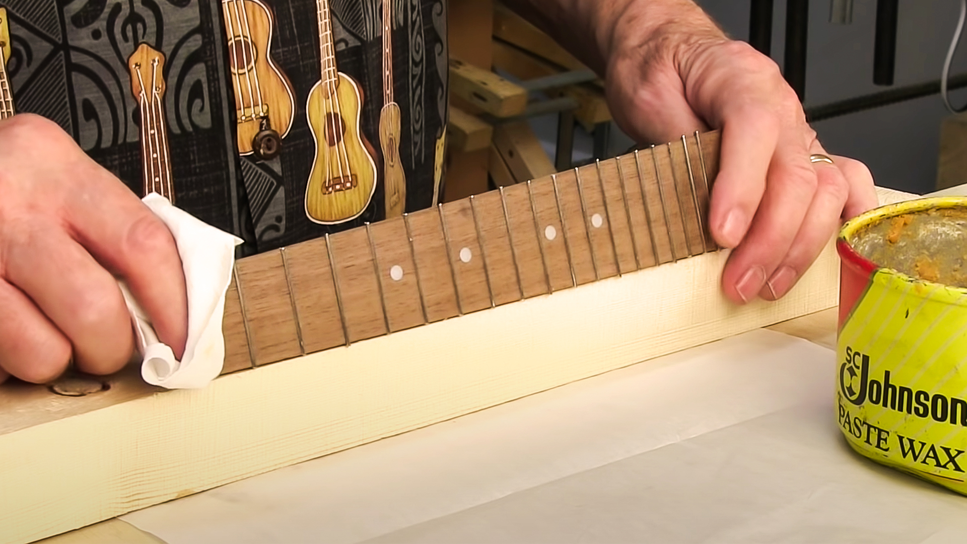 Hands holding fretboard on side to glue frets