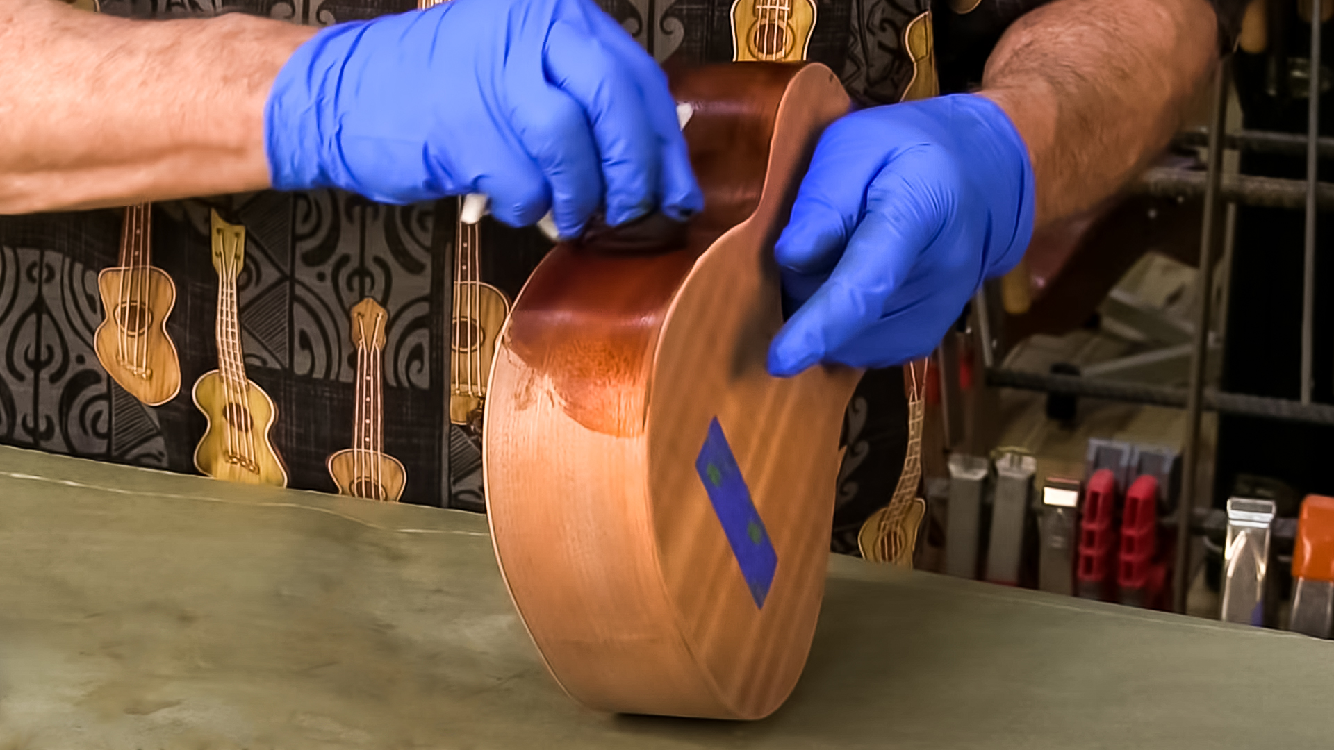 Gloved hands staining the body of the Ukulele