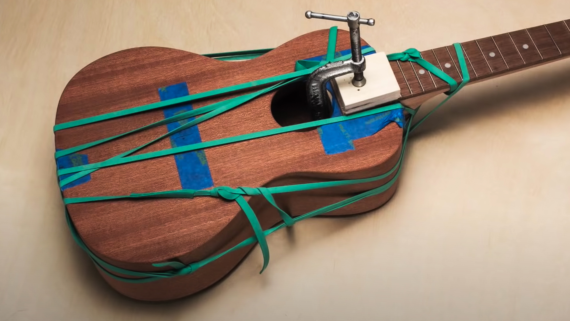 Rubber bands and clamps holding glued ukulele neck